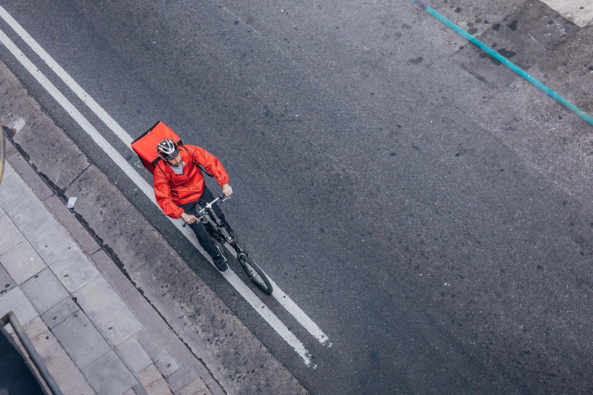 One man, delivery boy on bicycle, delivering pizza in city.